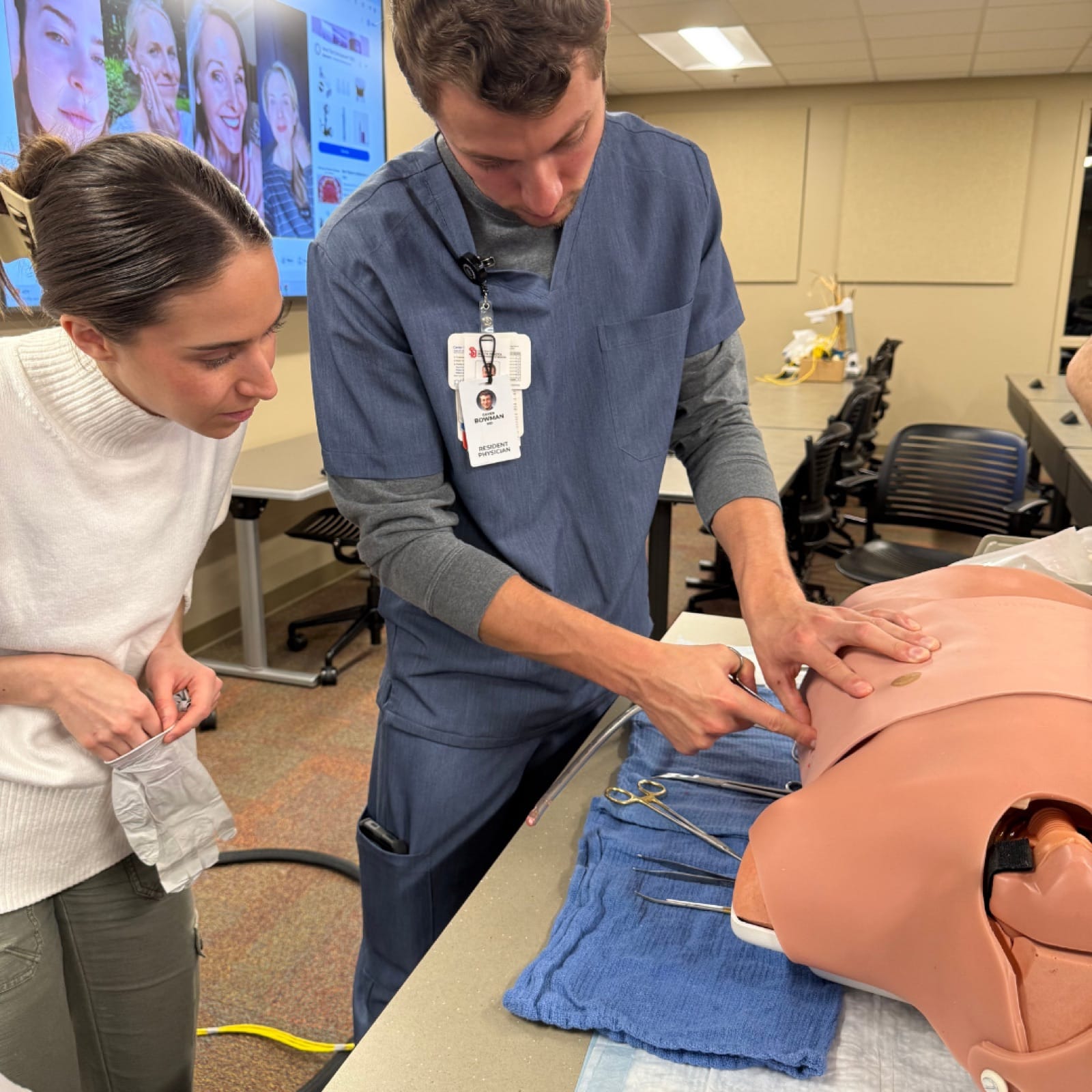 Two residents practicing a chest procedure on a procedural training torso