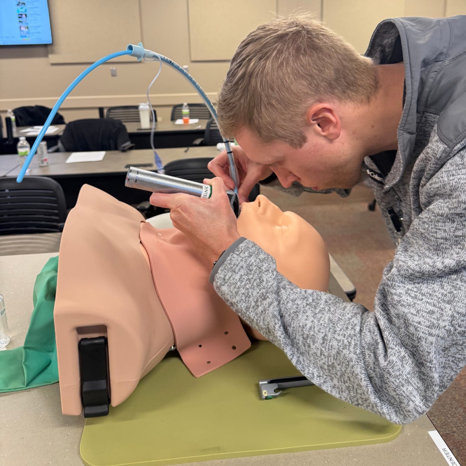 A resident using an otoscope on an ear-exam simulator