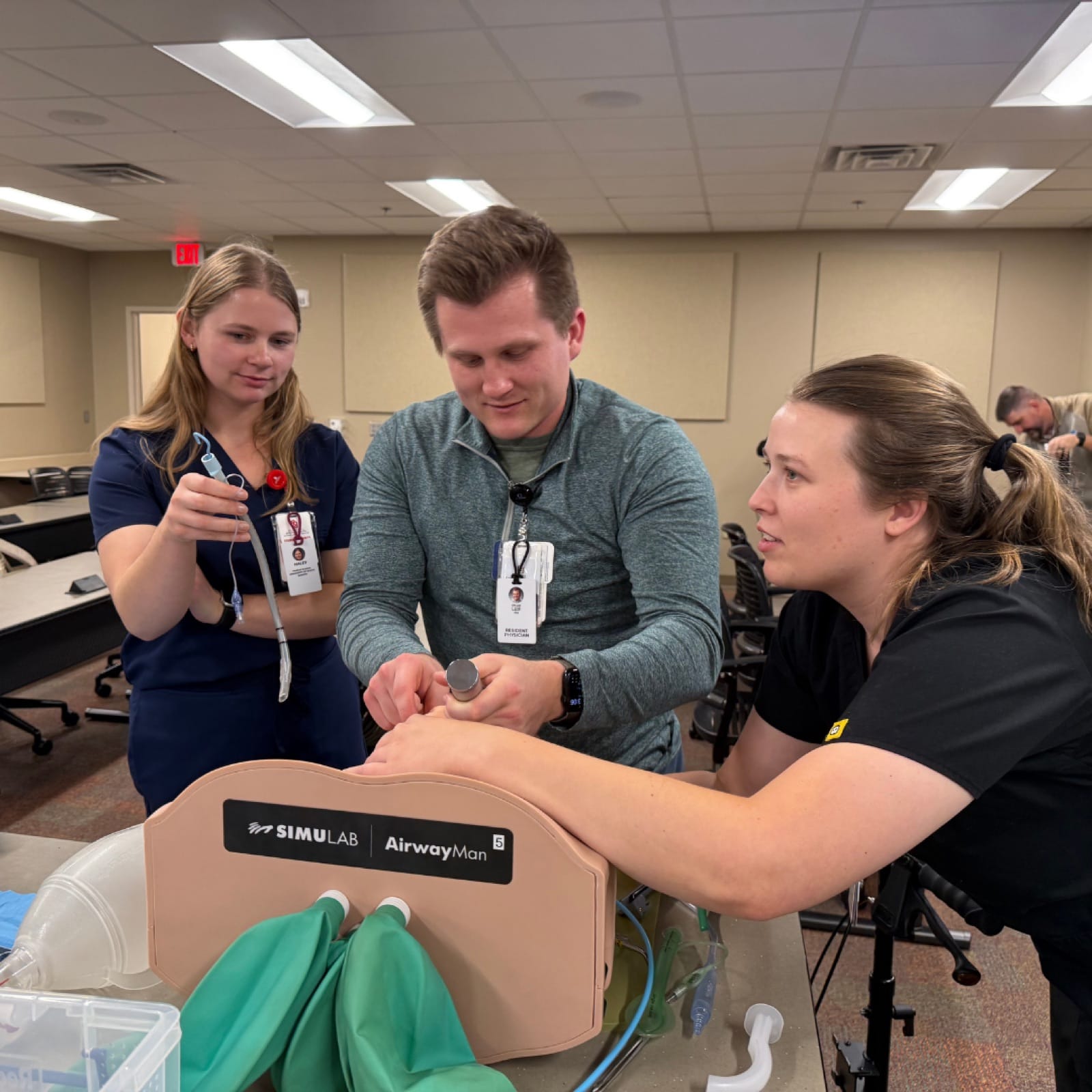 Three residents collaborating on a procedural-skills task box during a workshop